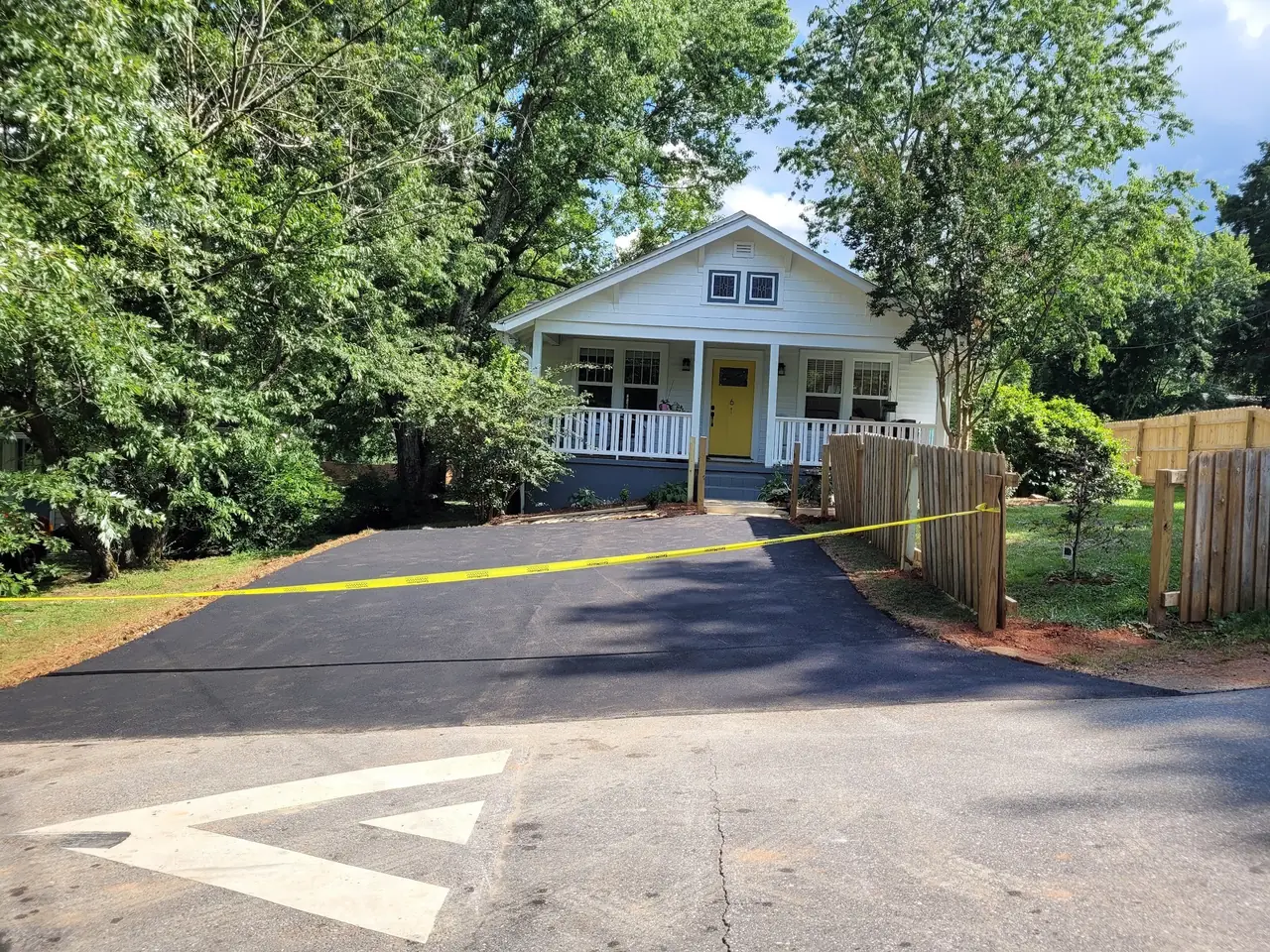 A new asphalt overlay in front of a home, taped off to cure