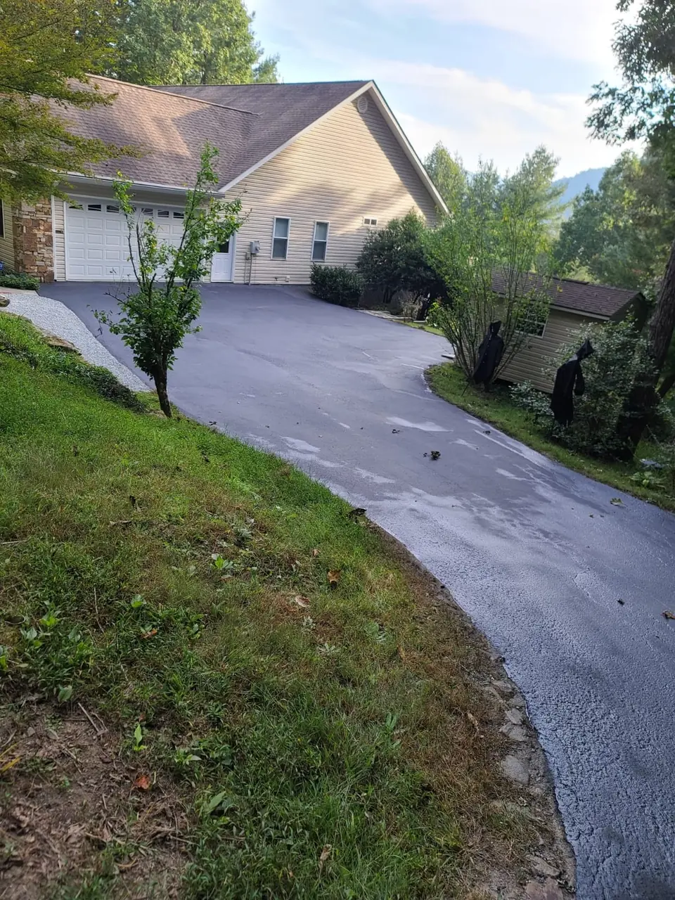 A steep new asphalt driveway climbing beside a mountain home